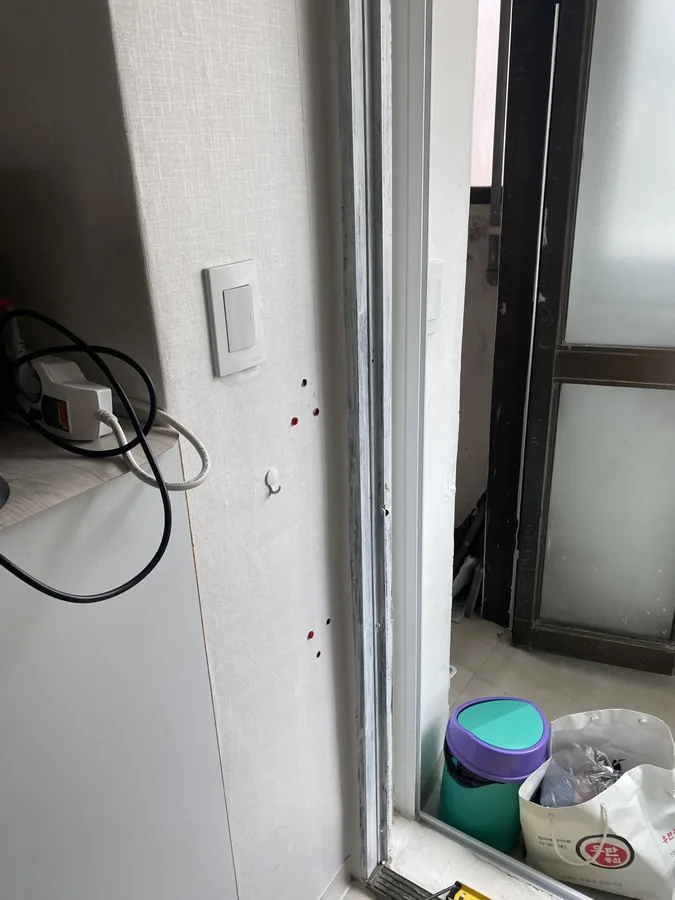 변기 옆 타일벽에 ㄱ자형 안전손잡이가 설치되고 위쪽에 수납장이 있는 모습